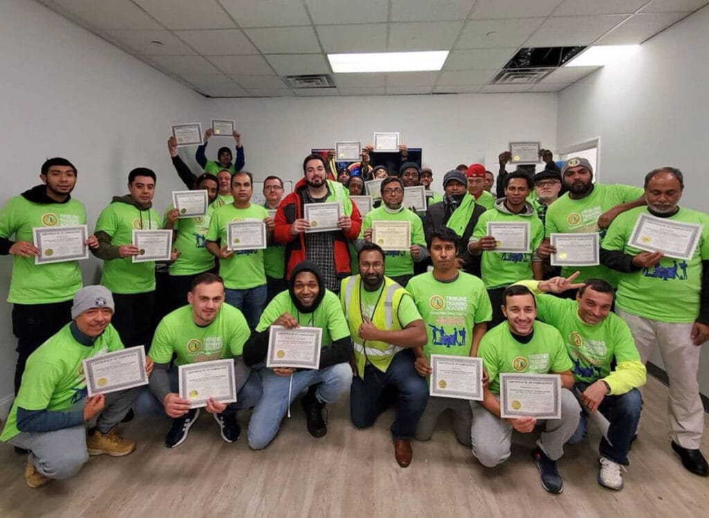 Class graduates holding certificates of completion.